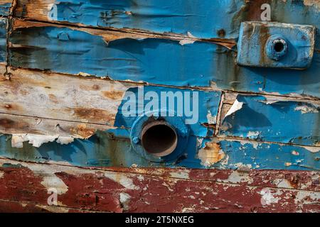 vecchia barca di legno malandata chic o angosciata con scrofalto arrugginito e vernice blu pelata. Foto Stock