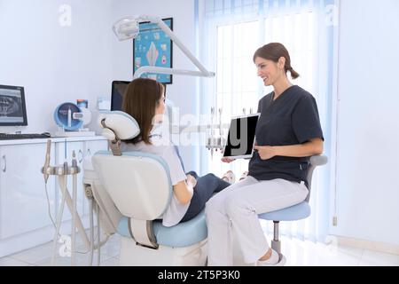 Dentista che mostra una clinica paziente femminile con tavoletta digitale Foto Stock