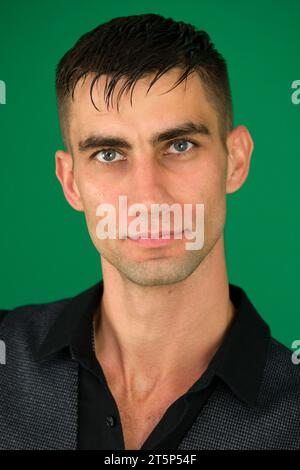 emozioni di un bel ragazzo su sfondo verde, primo piano cromakey, un giovane uomo dai capelli scuri. Giovane uomo d'affari isolato contro Foto Stock