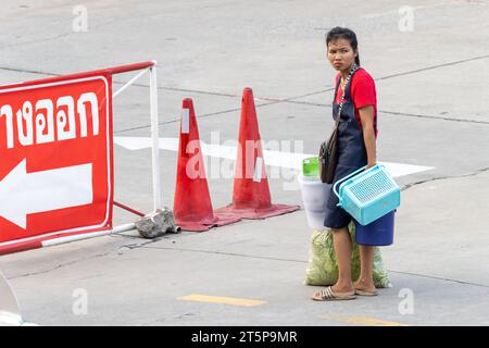 SAMUT PRAKAN, THAILANDIA, 03 novembre 2023, una donna esausta porta un carico pesante per strada Foto Stock