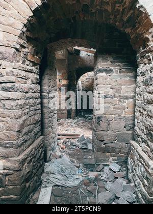 Vecchia chiesa abbandonata in rovina con muri in pietra. Passaggi, corridoi. Vista dall'interno. Foto Stock