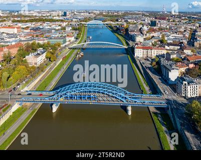 Cracovia, Polonia. 5 ponti sul fiume Vistola. Vista aerea. Ponte ad arco blu Pilsudski con tram e tram di fronte. Quindi passerella e bicicletta Foto Stock