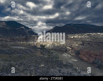 Le nuvole del mattino presto gettano ombre sulla terra, sul fiume e sulle montagne vicino a Cody, Wyoming. Vedi ovest verso l'ingresso del parco nazionale di Yellowstone. Foto Stock