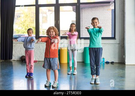 quattro allegri bambini preadolescenti in abbigliamento sportivo che si allungano e sorridono alla macchina fotografica, sport per bambini Foto Stock