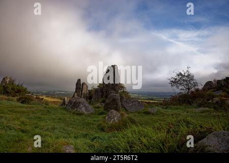 Rocce di granito frastagliate si stagliano su un pezzo di Cornish Heath vicino al villaggio di Roche mentre le nuvole di pioggia si spostano nella campagna, in Cornovaglia. Foto Stock