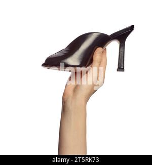 La mano di una donna che regge una scarpa estiva nera con tacco alto di tendenza isolata su uno sfondo bianco. Presentazione elegante delle scarpe in mano Foto Stock
