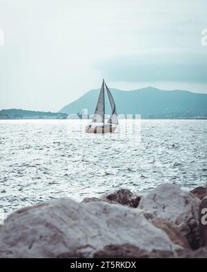 Una barca a vela che naviga attraverso acque tranquille in un pittoresco paesaggio di Tolone Foto Stock