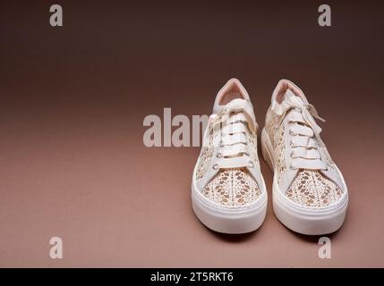 Sneaker di tendenza in maglia pastello con suole in gomma spessa bianca su sfondo marrone sfumato con spazio per la copia. Eleganti scarpe estive da donna Foto Stock