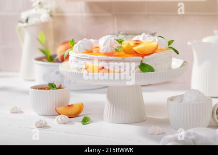 Gustosa meringa di pesca servita come dessert primaverile. Meringa di pesca con zucchero a torta e frutta. Foto Stock