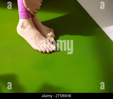 I piedi della donna sul tappetino verde per lo yoga si rilassano dopo il massaggio per alleviare la tensione muscolare. Riduzione del dolore muscolare, aumento del flusso sanguigno. Fisioterapia, Foto Stock