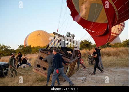 L'equipaggio accende i bruciatori, sollevando la mongolfiera e il cesto di vimini per un viaggio all'alba sui paesaggi della Cappadocia. Foto Stock