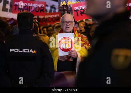 Madrid, Spagna. 6 novembre 2023. Un uomo che indossa una bandiera spagnola tiene un cartello con la scritta "Nessuna amnistia” durante una protesta davanti alla sede del PSOE del partito socialista contro il governo di Pedro Sanchez e la possibile approvazione di un'amnistia per i leader separatisti catalani che il governo sta negoziando per garantire l'investitura del socialista candidato. Gruppi di estrema destra come il partito VOX hanno sostenuto le proteste che sono state condotte anche in diverse città spagnole. Crediti: Marcos del Mazo/Alamy Live News Foto Stock