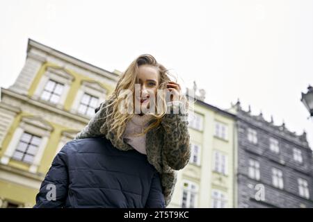 Ragazza allegra con i capelli morbidi sulla spalla del suo ragazzo. Foto in città, un uomo porta una donna sulla spalla. Giovane coppia appassionata, Foto Stock