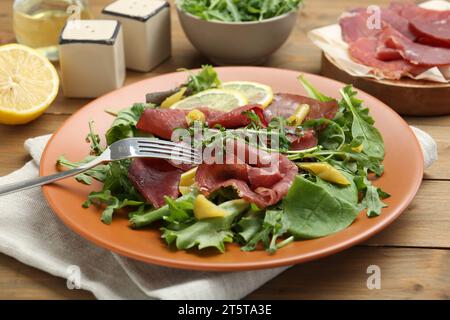 Deliziosa insalata bresaola servita su un tavolo di legno, primo piano Foto Stock