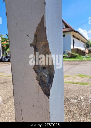 Incrinature nei pilastri di costruzione danneggiati. Pilastro di cemento incrinato di una vecchia casa. Fratture profonde e chiare, sulla superficie anteriore di un vecchio montante di cemento. Foto Stock