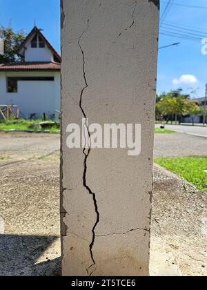 Incrinature nei pilastri di costruzione danneggiati. Pilastro di cemento incrinato di una vecchia casa. Fratture profonde e chiare, sulla superficie anteriore di un vecchio montante di cemento. Foto Stock