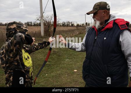 Zaporizhzhia, Ucraina. 5 novembre 2023. Un giovane ragazzo ascolta l'allenatore durante la pratica di tiro con l'arco nel club di tiro con l'arco dei cosacchi "Bayda". La guerra tra Israele e Gaza sta "togliendo l'attenzione” dal conflitto in Ucraina, ha ammesso il presidente del paese Volodymyr Zelensky. E ha negato che i combattimenti in Ucraina avessero raggiunto uno stallo, nonostante una recente valutazione in tal senso da parte del generale militare più importante del paese. La controffensiva dell'Ucraina nel sud ha finora fatto pochi progressi. Credito: SOPA Images Limited/Alamy Live News Foto Stock