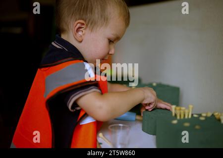 Piccolo bambino vestito da muratore che gioca a casa Foto Stock