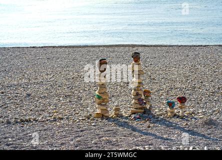 figure fatte di pietre sulla spiaggia sullo sfondo del mare. Una figura verticale fatta di pietre si erge sullo sfondo dell'acqua. Foto Stock