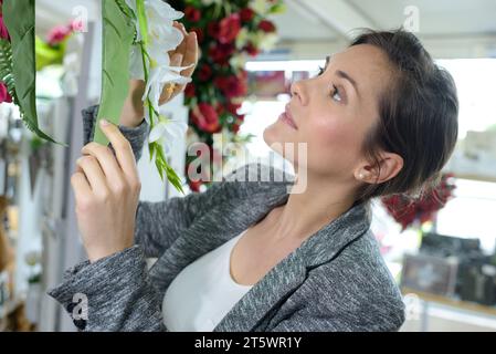 donna che sceglie fiori di plastica per un funerale Foto Stock