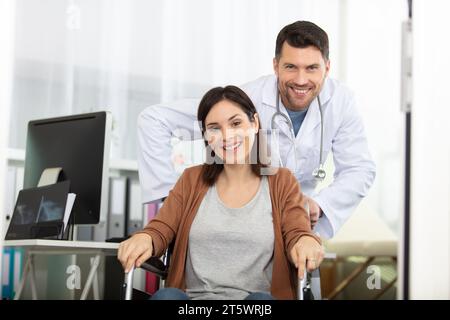il medico maschio spinge la paziente in sedia a rotelle Foto Stock