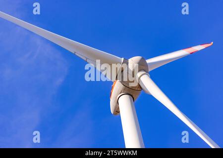 Dettagli del rotore e delle pale di una turbina eolica ritagliata davanti a un cielo blu Foto Stock