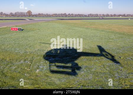 Ombra dall'elicottero di decollo sull'erba vicino alla pista dell'aeroporto olandese di Zestienhoven vicino a Rotterdam Foto Stock