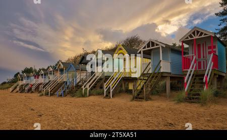 La tempesta Ciaran crea un cielo drammatico mentre l'ultimo sole della giornata illumina le nuvole di tempesta sulle capanne sulla spiaggia di Wells vicino al mare. Foto Stock