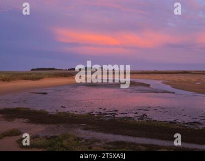 Un tramonto profondo e vibrante sull'estuario della East Fleet a Wells Next the Sea sulla costa del Norfolk settentrionale. Foto Stock