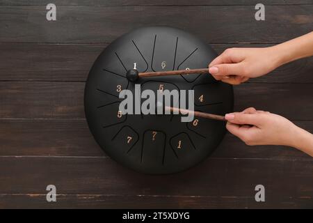 Mani femminili con bastoncini che giocano a glucofone su sfondo marrone di legno Foto Stock