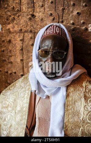 NIGER Zinder Sultan Palace NIGER, Zinder, palazzo del sultano di DAMAGARAM El Hadji ABOUBACAR OUMAROU SANDA, ritrattistica di uomo sconosciuto all'ingresso, con indosso l'indumento Boubou realizzato in tessuto damascico *** Sultans Palast, Porträt eines Mannes im Gewand Boubou aus Damast Gewebe Zinder Niger Credit: Imago/Alamy Live News Foto Stock