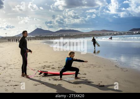 Spagna, Lanzarote, Caleta de Famara: Il padre insegna al figlio a fare surf sulla spiaggia di Famara Foto Stock