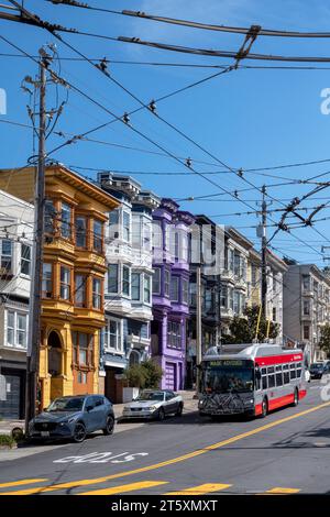 Castro Street, San Francisco, California, USA - 23 aprile 2023: Case colorate su una strada ripida con auto parcheggiate su strada asfaltata con segni gialli e. Foto Stock