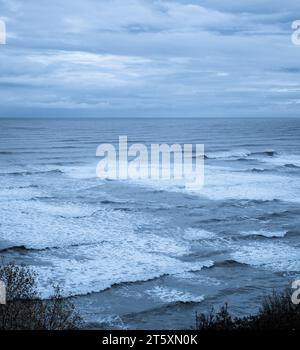 Onde che si infrangono sulla spiaggia dalla cima della scogliera di Robin Hood's Bay nel North Yorkshire. Foto Stock