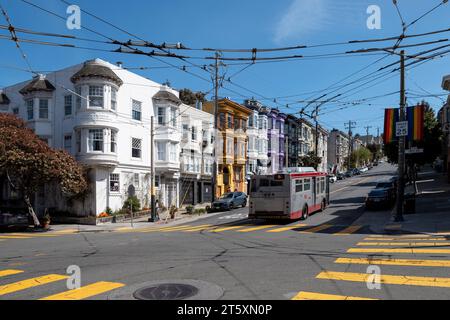 Castro Street, San Francisco, California, USA - 23 aprile 2023: Case colorate su una strada ripida con auto parcheggiate su strada asfaltata con segni gialli e. Foto Stock