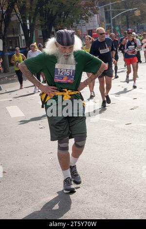 Un corridore più vecchio con i capelli grandi e la barba grigia sembra battere dopo appena 16 chilometri dalla Maratona di New York. A Williamsburg, Brooklyn, New York. Foto Stock