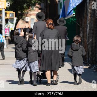 Moda chassidica. Uomini vestiti allo stesso modo e figlie vestiti allo stesso modo. Su Bedford Avenue a Brooklyn. Foto Stock