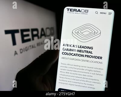 Persona che possiede il cellulare con la pagina Web dell'azienda sudafricana Teraco Data Environments davanti al logo. Concentrarsi sul centro del display del telefono. Foto Stock