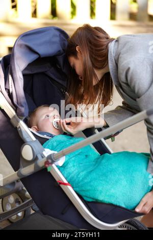 Madre, bambino e succhietto in passeggino per camminare, insieme o legare per esercizio, salute o benessere. Giovane donna, neonato e dare di manichino per Foto Stock