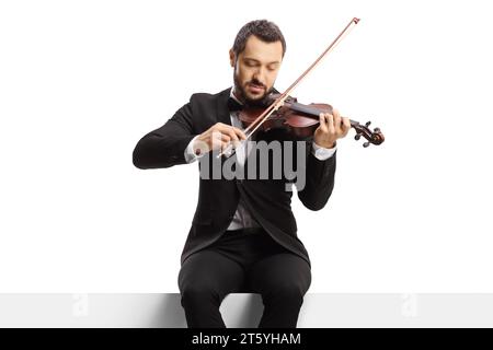 Violinista seduto su un pannello vuoto e suona un violino isolato su sfondo bianco Foto Stock