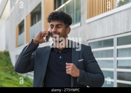 Ritratto ravvicinato di un giovane e sicuro uomo arabo che parla al telefono all'aperto Foto Stock