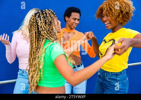 Donna latina e afro-americana che danza salsa insieme con gli amici accanto a uno sfondo blu Foto Stock