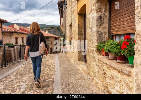 Donna turistica che cammina per le strade acciottolate del borgo medievale di Frias, Burgos. Foto Stock