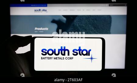 Persona che possiede uno smartphone con il logo della società canadese South Star Battery Metals Corp. Davanti al sito Web. Concentrarsi sul display del telefono. Foto Stock