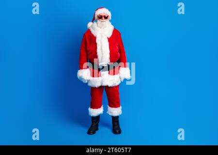 Foto a grandezza naturale di un anziano pensionato in stand promo Black friday vestito da elegante costume da babbo natale isolato su sfondo blu Foto Stock