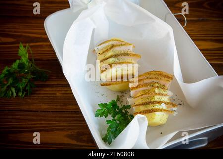 Patate crude ripiene di strutto e spezie, preparate per cuocere in carta da forno. Foto Stock