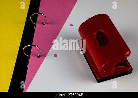 Aprire la rilegatura ad anello con il cartoncino colorato, il foglio di carta bianco e il perforatore Foto Stock