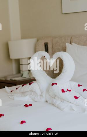 Camera dolce in vacanza, decorazione degli asciugamani Swan sul letto con cuscino bianco all'interno della camera da letto. Foto Stock