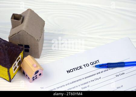 Avviso di uscita o di sfratto avviso di carta bianca pronta per il riempimento con piccole case di giocattoli sul tavolo da vicino Foto Stock