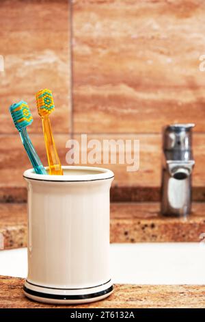 Modello verticale con spazzolini nella tazza del lavandino del bagno. Ambienti sanitari e igienici Foto Stock